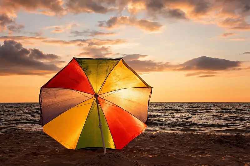 Colourful beach umbrella on the sand at sunset