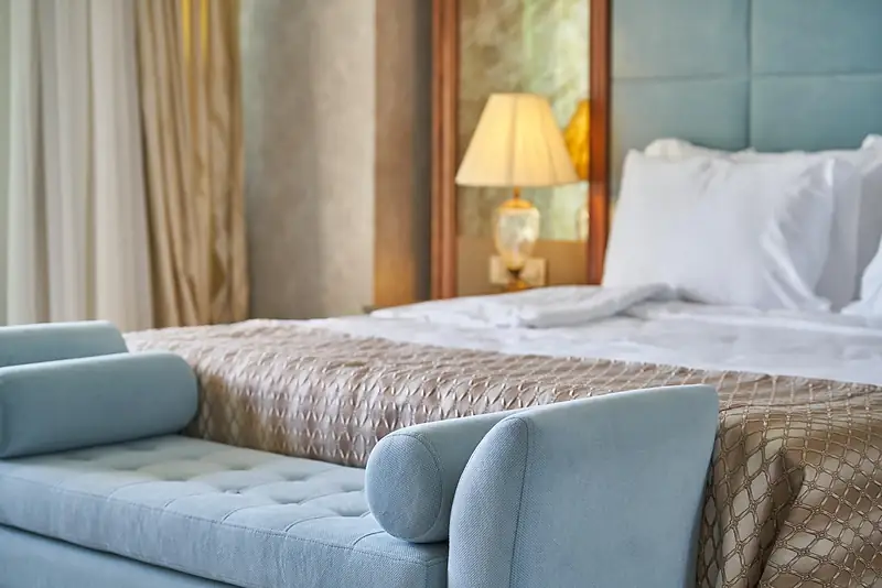 Made-up double bed and sofa in a calm hotel room
